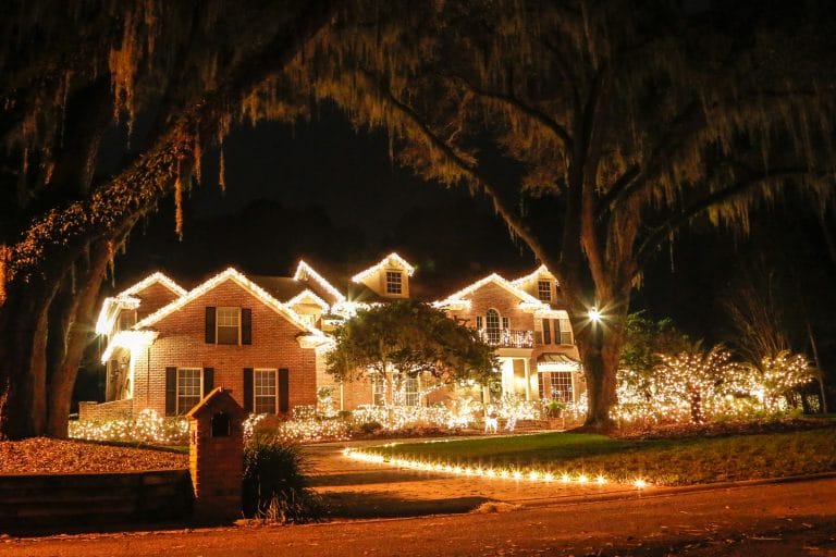 Lights installed on rooflines of house with lit up trees and bushes.